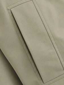 Detail of grey-green hooded jacket showing fabric texture and double-stitched pocket flap