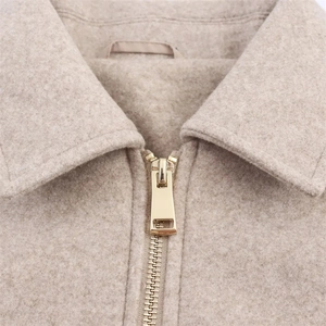 Detail of soft wool lapel and minimalist gold zipper on beige oversized jacket