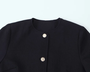Detail of black tweed jacket with golden relief buttons and woven texture collar