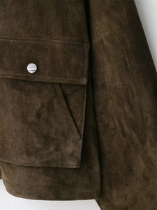 Détail d'une veste en daim marron vintage avec poche à rabat et bouton-pression argent