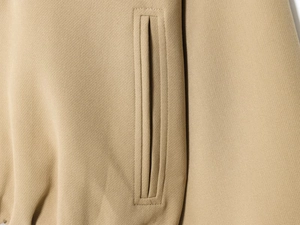 Detailed close-up of vertical welt pocket on khaki jacket showing premium stitching and fabric
