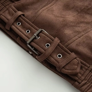 Detail einer dunkelbraunen Wildlederjacke mit verstellbarer Schnalle und sauberen Nähten