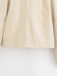 Detail view of smooth beige trench coat hem and sleeves with premium stitching texture
