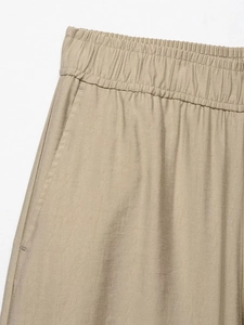 Detail of elastic waistband and side pockets on khaki wide-leg trousers fabric