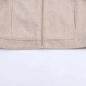 Detailed macro view of high-quality light beige fleece fabric and golden metal zipper