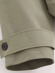 Macro view of hooded windbreaker cuff with adjustable strap and dark brown button detail