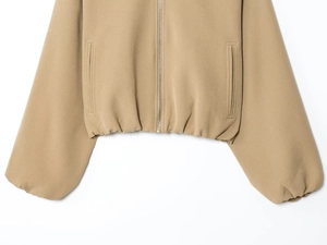 Detail of khaki zip-up jacket showing smooth metal zipper and symmetrical side pockets