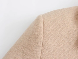 Macro view of beige wool coat shoulder seam detailing with diagonal twill fabric texture