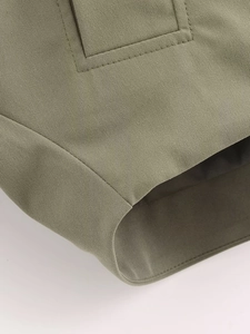 Detailed close-up of olive green poncho jacket fabric with visible twill texture and stitching