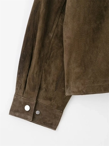Détail du poignet d'une veste en daim marron avec bouton pression et coutures rétro
