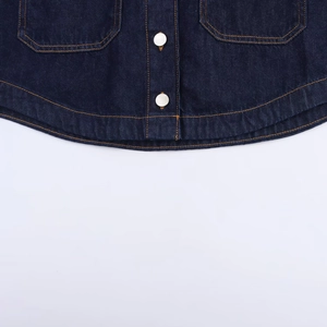 Detail of dark blue denim shirt hem with silver metal buttons and neat stitching