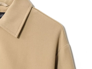 Detailed macro view of khaki jacket collar with black size S label and stitching