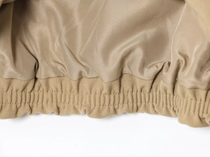 Detailed macro view of khaki puffer jacket showing elastic hem and satin lining