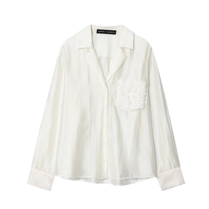 Close-up of white silk shirt featuring a unique embroidered pocket and classic lapel