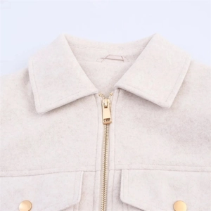 Detailed macro view of the soft beige wool jacket featuring a metal zipper and lapel collar