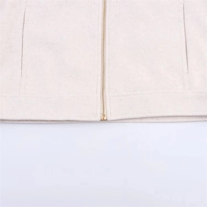 Detail of cream zippered jacket showing golden metal zipper and neat hemline stitching
