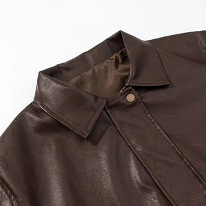 Detailed macro view of vintage brown PU leather jacket featuring retro copper snap buttons