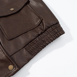 Close-up of brown PU leather jacket featuring vintage metal buttons and pocket detail