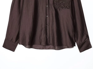 Detailed view of the dark brown silk-like shirt's embroidered pocket and fabric texture