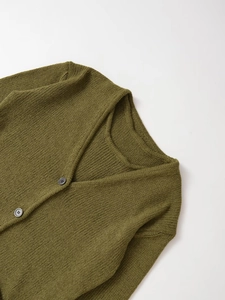 Close-up of grass green cotton knit cardigan with V-neck and textured wood-style buttons