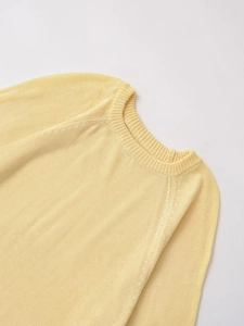 Close-up of ribbed crew neck and raglan sleeves on a light yellow knit sweater