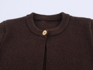 Detail of dark brown knit cardigan with ribbed collar and golden textured button