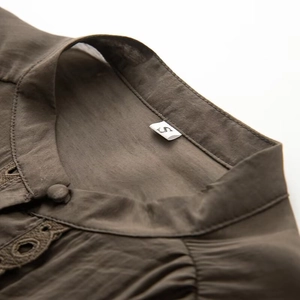 Detailed close-up of khaki stand collar shirt with delicate lace trim and fabric buttons