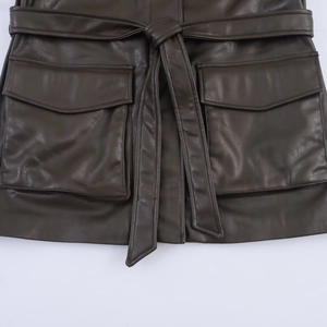Detail of faux leather jacket featuring adjustable waist belt and large flap pockets