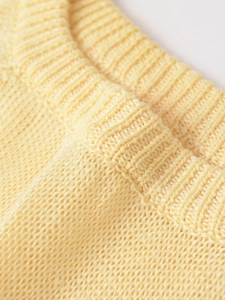 Detailed close-up of light yellow knit sweater showing fine ribbed texture and soft fabric