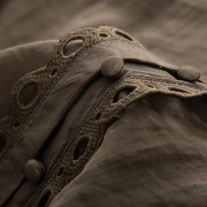 Macro detail of coffee brown shirt showing lace trim, fabric texture and fabric buttons