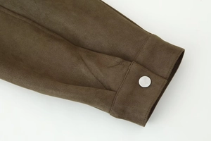Detailed close-up of brown faux suede jacket cuff with silver metal snap button