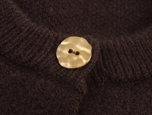 Detail of dark coffee knit cardigan featuring a textured matte gold irregular button