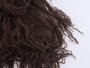 Detailed macro view of dark brown knitted fabric texture with long decorative fringe edge