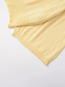 Close-up of pale yellow knit sweater showing fine texture and ribbed cuff detail