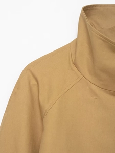 Close-up of khaki stand-up collar and raglan sleeve stitching on short trench coat jacket