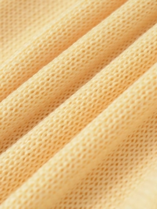 Macro shot of yellow knit fabric showing soft honeycomb texture and premium woven detail