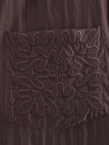 Close-up of deep brown shirt pocket with intricate floral embroidery and striped texture