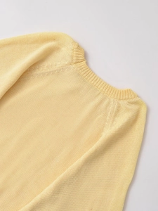Detail of soft pale yellow knit sweater featuring ribbed crew neck and fine woven texture
