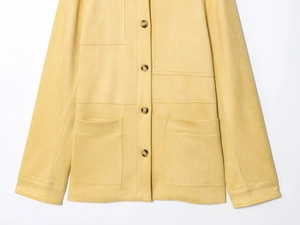 Detail of ginger yellow faux suede jacket featuring large patch pockets and marble buttons