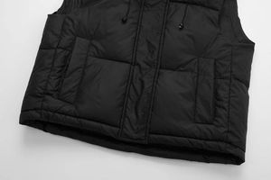 Close-up of black quilted vest featuring deep symmetrical pockets and windproof flap detail