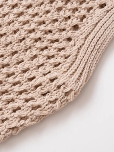 Nahaufnahme einer beigen Strickweste mit Lochmuster-Häkelarbeit und Rippstrickkante