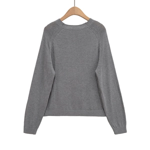 Détails du pull en maille grise avec col rond montrant la texture fine du tricotage