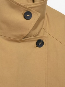 Close-up of stand-up collar and black buttons on a khaki short trench coat jacket