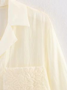 Close-up of cream long sleeve shirt featuring intricate floral embroidery on chest pocket