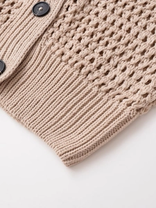 Detailansicht des groben Strickmusters und der schwarzen runden Knöpfe an der V-Weste