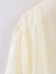Detail of beige long sleeve top showing shoulder seam and soft woven fabric texture