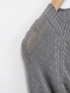 Détail d'un pull en maille grise avec motif ajouré et col rond côtelé sur cintre