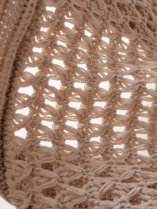 Makroaufnahme der beigen Häkeltextur mit detailliertem, hohlem Netzstrickmuster für Damen