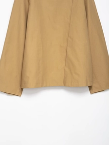 Detail of khaki cropped jacket showing structured cotton twill fabric and stitching