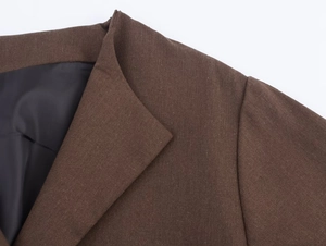 Detail of dark brown notched lapel jacket with textured woven fabric and black silky lining